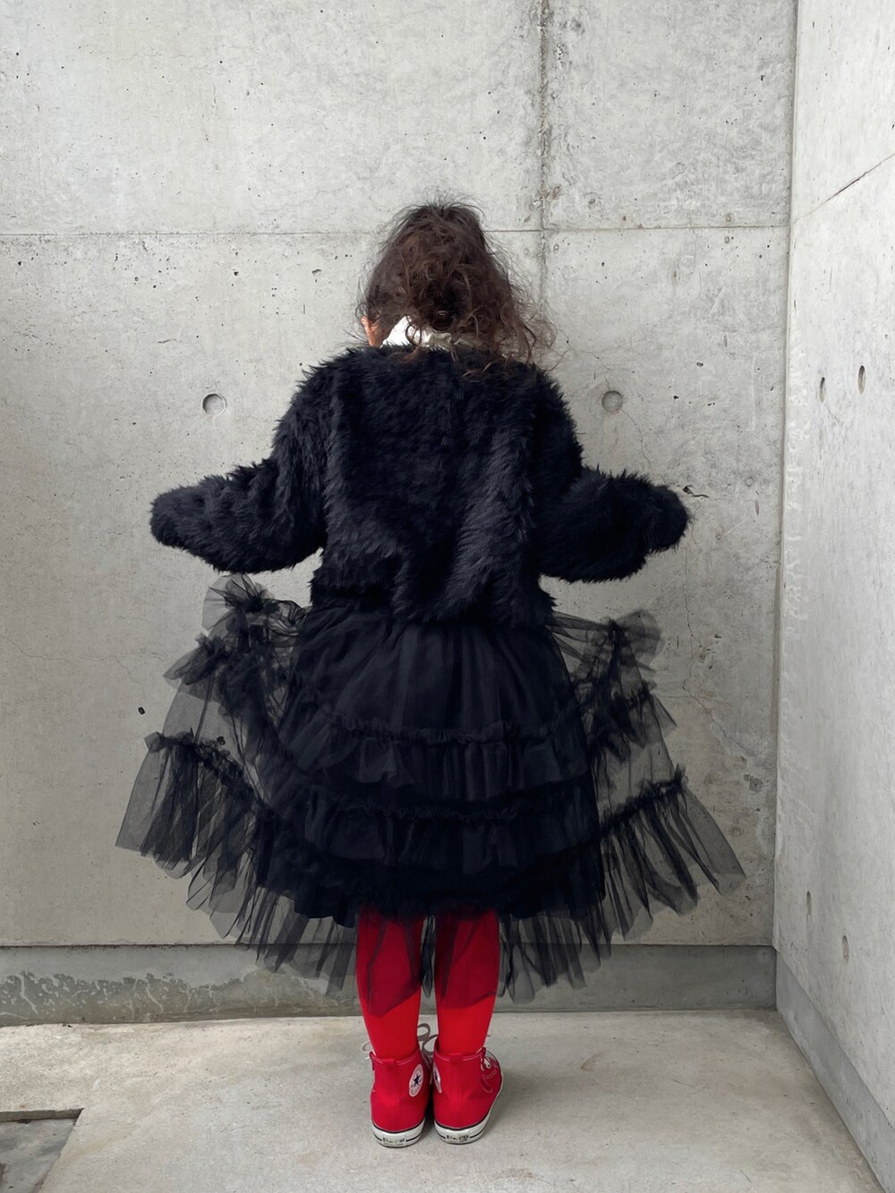 ブラック系のスカート、ホワイト系のニット/セーター、レッド系のスニーカーを着用したキッズの冬コーディネートの5枚目の写真