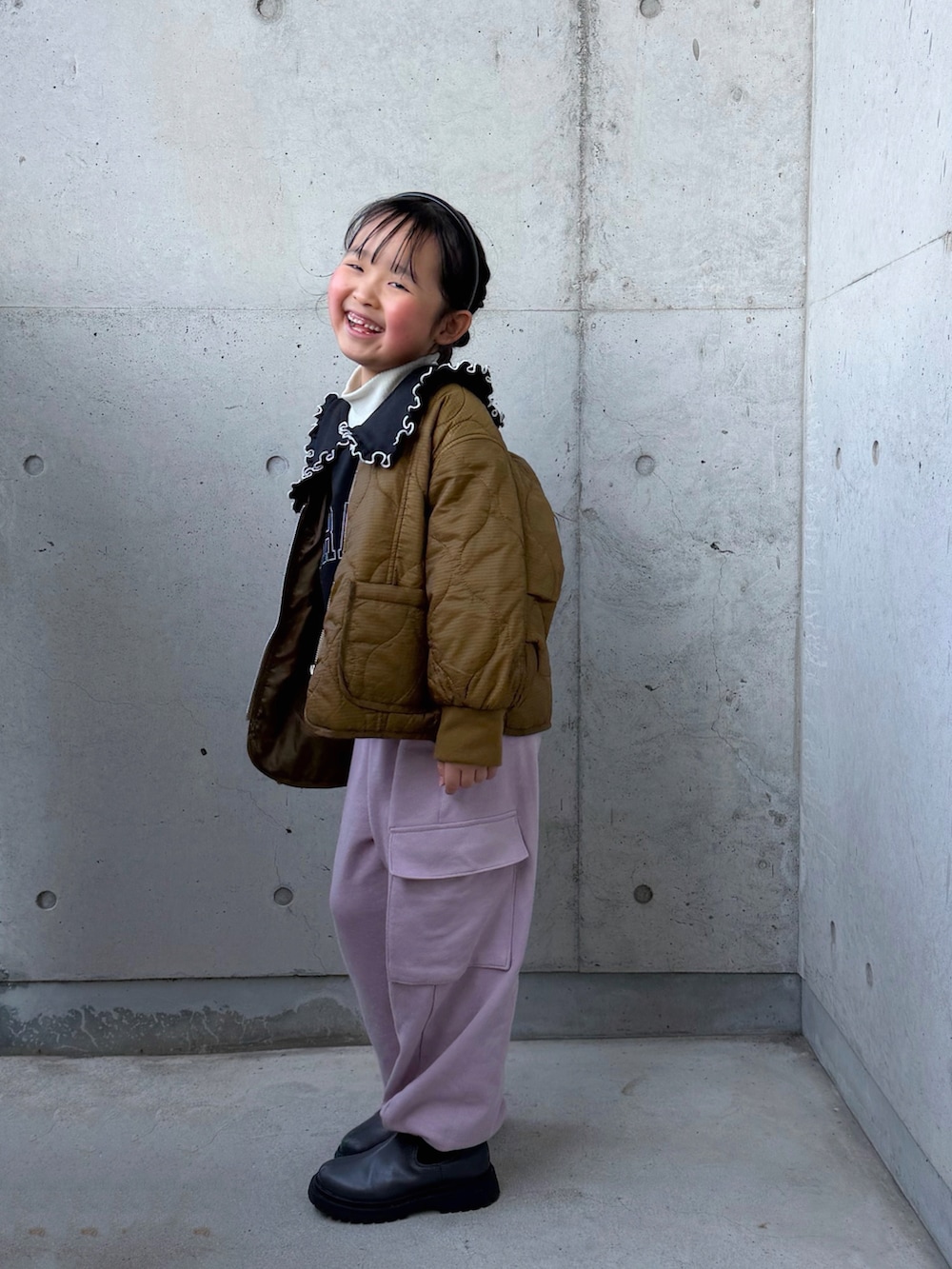 ブラック系のスウェット、ピンク系のカーゴパンツ、グレー系のブーツを着用したキッズの冬コーディネートの2枚目の写真