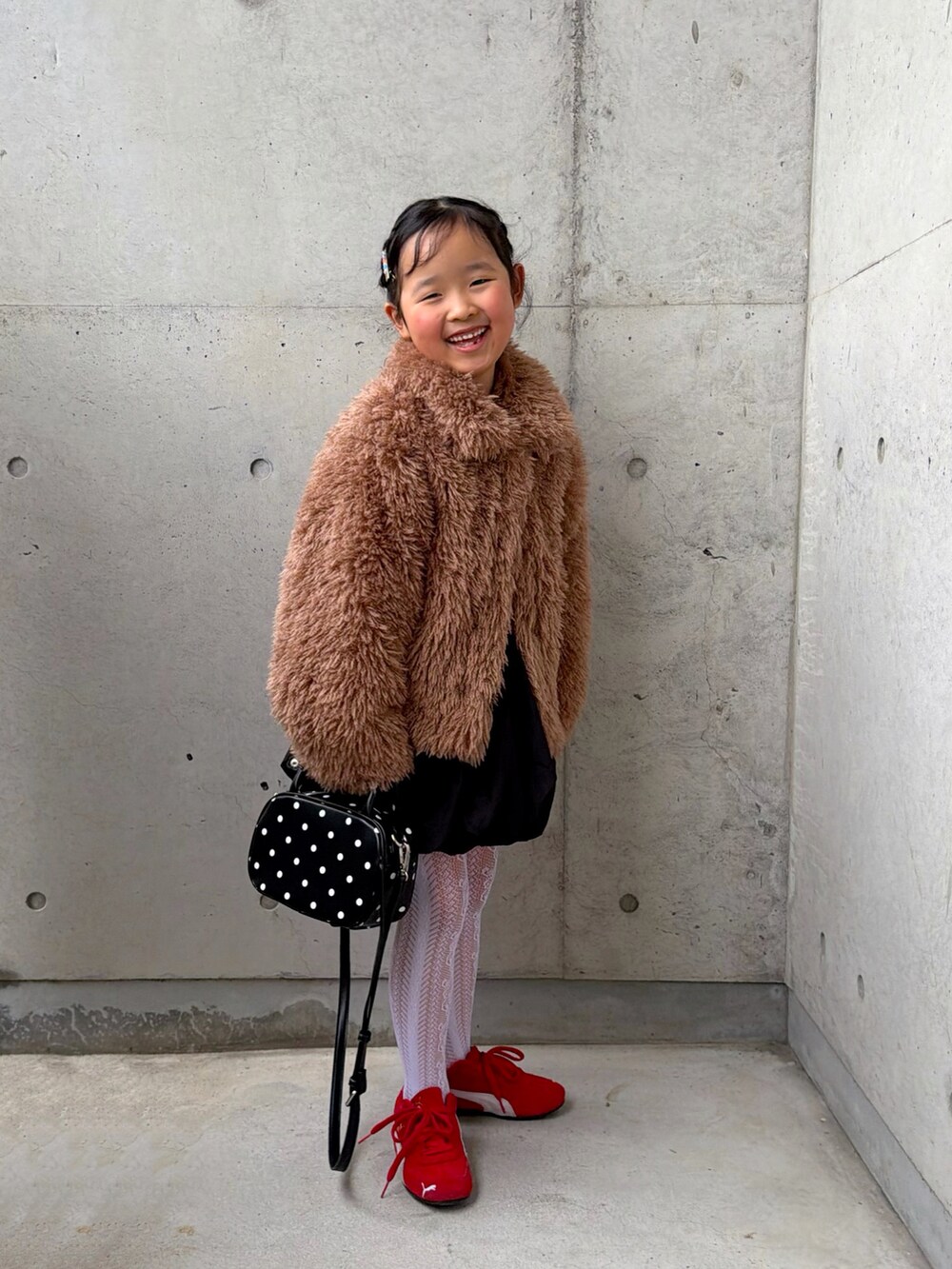 ブラウン系のブルゾン、ブラック系のスカート、ホワイト系のTシャツ/カットソーを着用したキッズの冬コーディネートの4枚目の写真