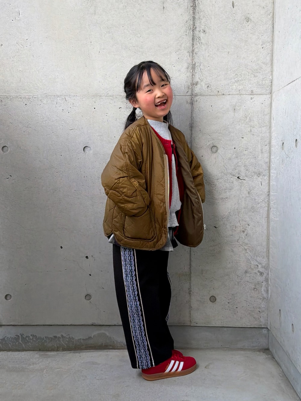 グレー系のスウェット、ブラック系のスカート、レッド系のスニーカーを着用したキッズの冬コーディネートの4枚目の写真