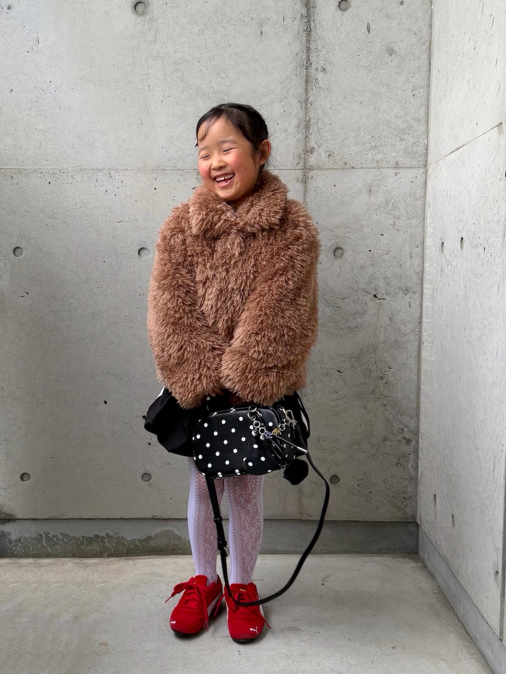 ブラウン系のブルゾン、ブラック系のスカート、ホワイト系のTシャツ/カットソーを着用したキッズの冬コーディネートの5枚目の写真