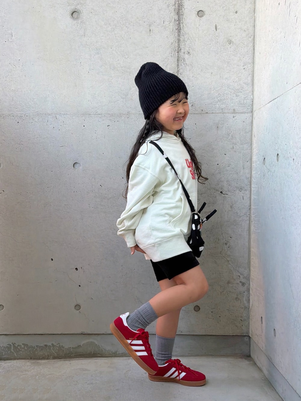 ホワイト系のパーカー、ブラック系のショルダーバッグ、レッド系のスニーカーを着用したキッズの冬コーディネートの3枚目の写真