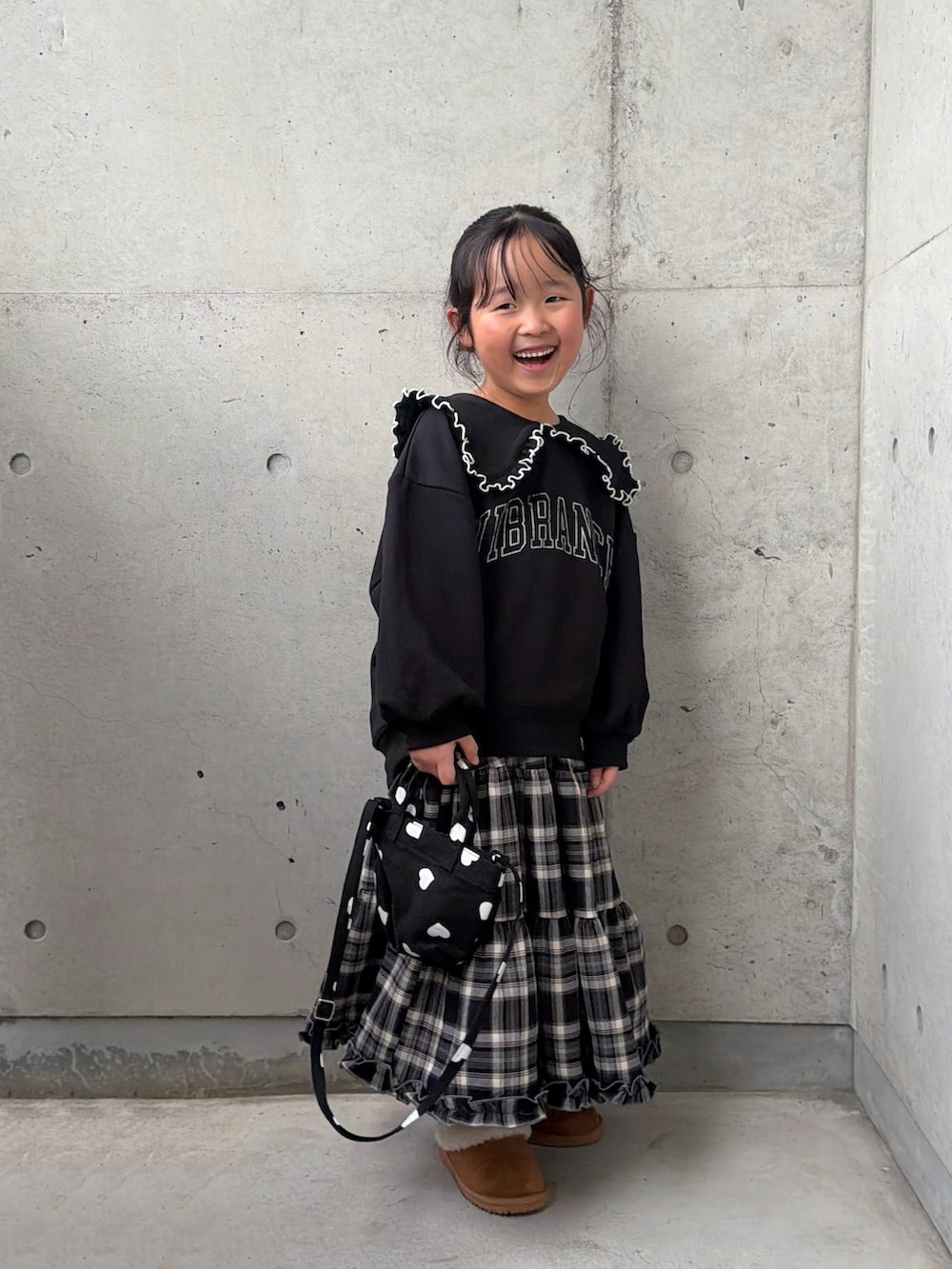 ブラック系のスウェット、ブラウン系のスカート、ブラック系のショルダーバッグを着用したキッズの秋コーディネートの4枚目の写真
