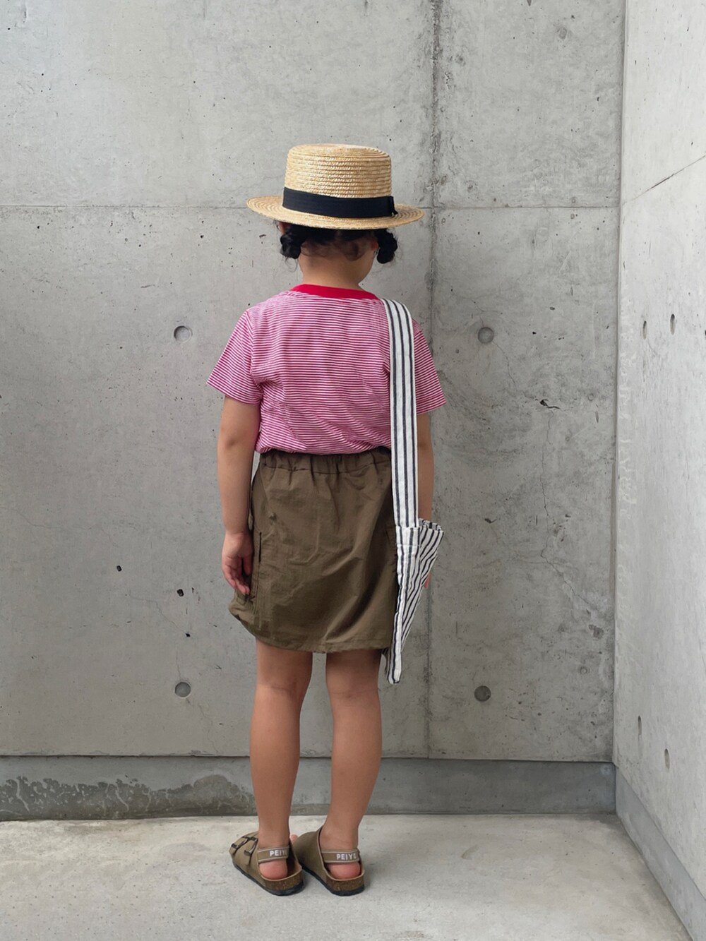 レッド系のTシャツ/カットソー、グリーン系のスカート、ホワイト系のバッグを着用したキッズの夏コーディネートの3枚目の写真
