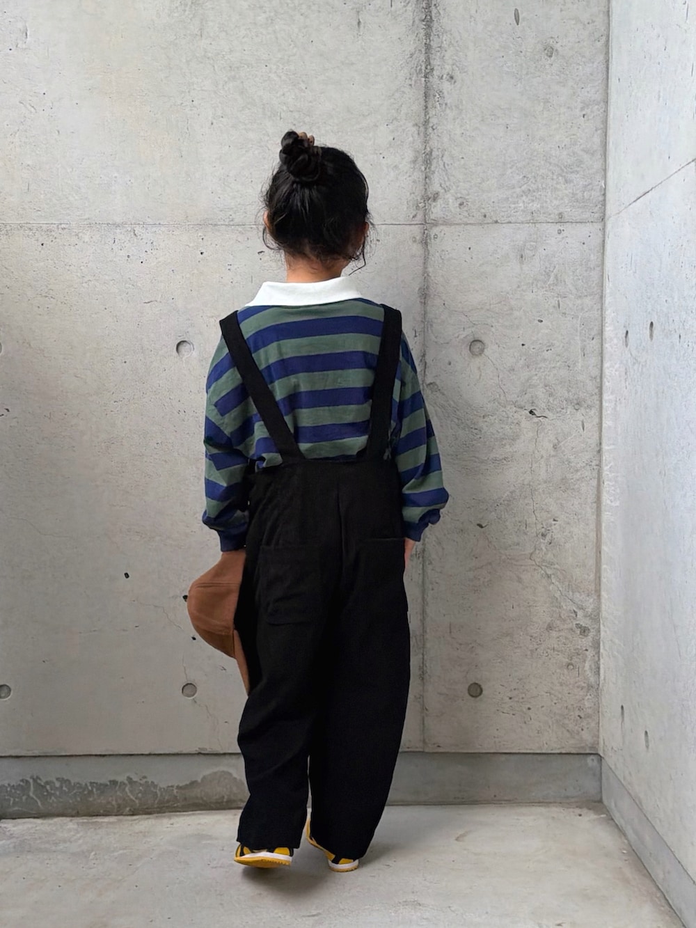 グリーン系のポロシャツ、イエロー系のスニーカー、ブラック系のサロペット/オーバーオールを着用したキッズの秋コーディネートの5枚目の写真