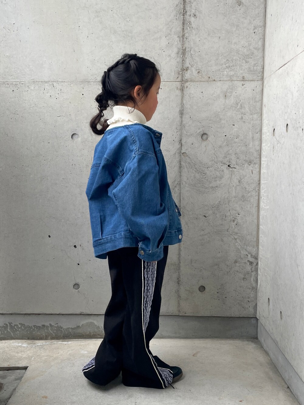 ブラック系のパンツ、ブルー系のデニムジャケット、ホワイト系のニット/セーターを着用したキッズの春コーディネートの4枚目の写真