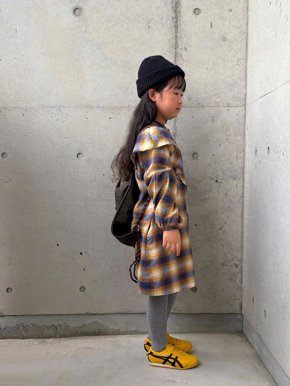 イエロー系のワンピース、イエロー系のスニーカー、ブラック系のバックパック/リュックを着用したキッズの春コーディネートの4枚目の写真