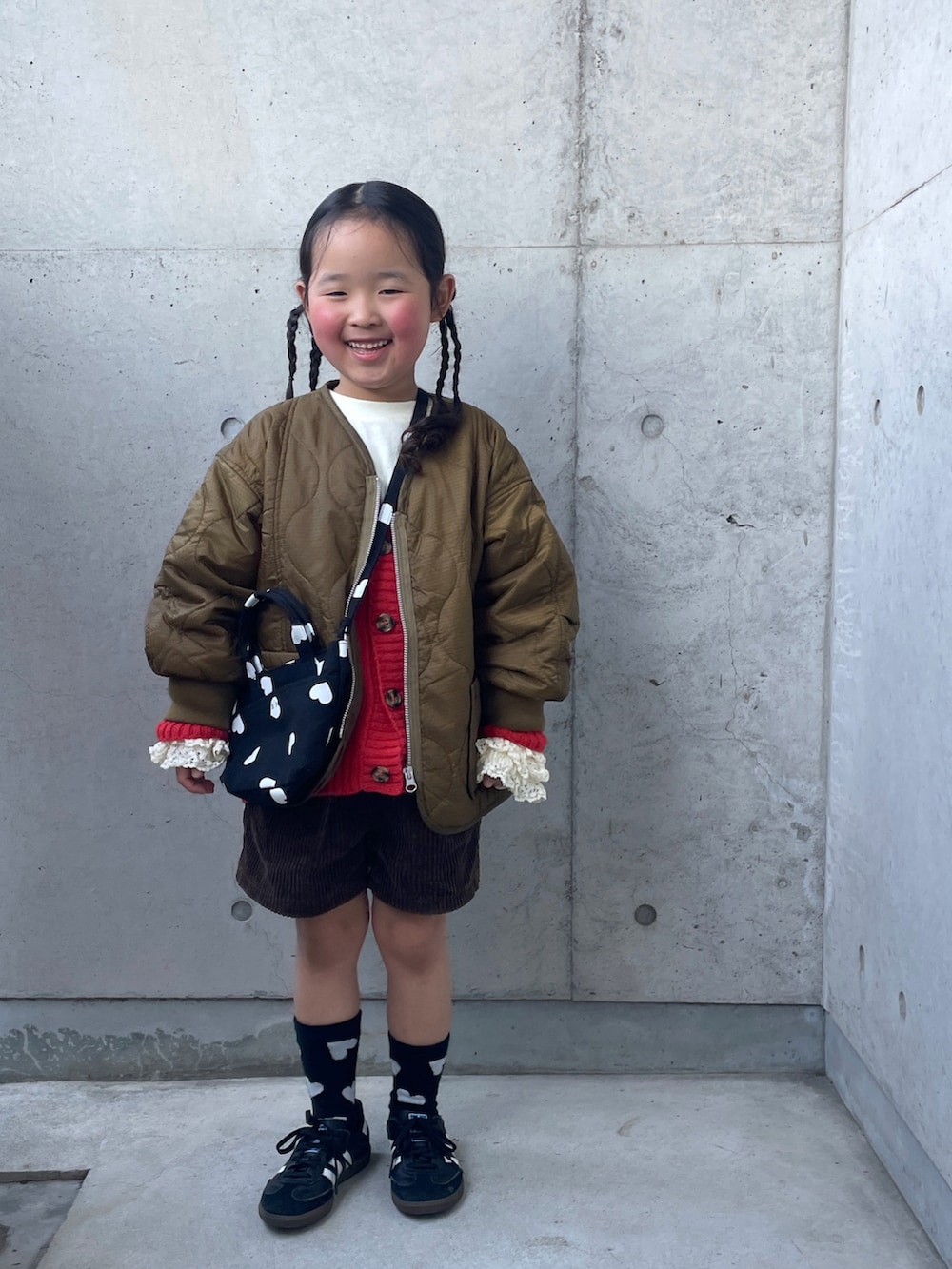 ブラウン系のその他パンツ、ブラック系のショルダーバッグ、オレンジ系のカーディガン/ボレロを着用したキッズの冬コーディネートの4枚目の写真