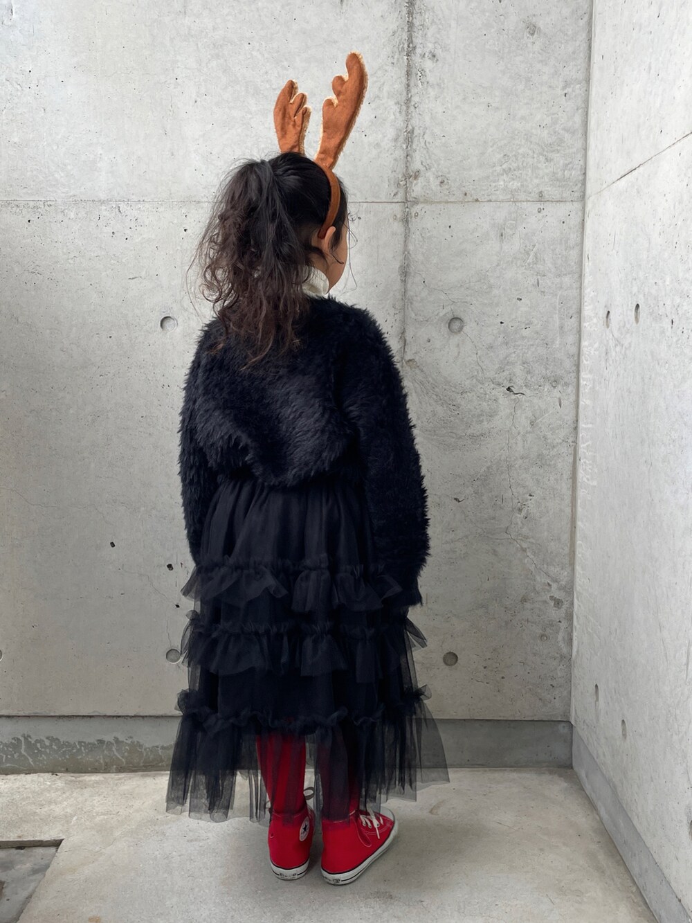 ブラック系のスカート、ホワイト系のニット/セーター、レッド系のスニーカーを着用したキッズの冬コーディネートの3枚目の写真