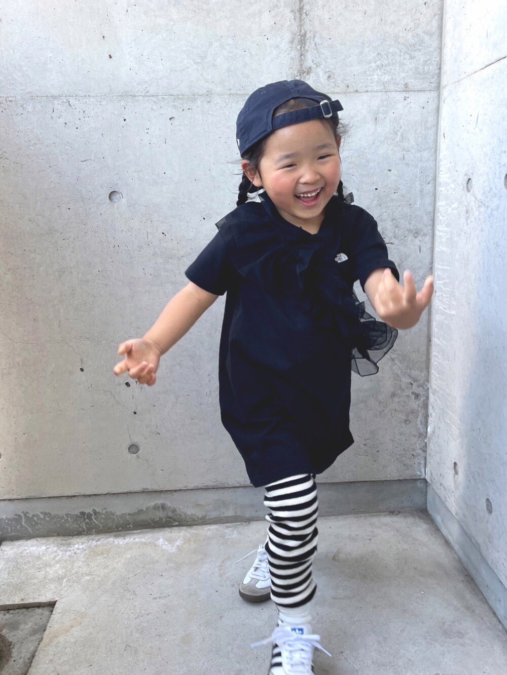 ブラック系のワンピース、ホワイト系のスニーカー、ブラック系のバレッタ/ヘアクリップを着用したキッズの春コーディネートの3枚目の写真