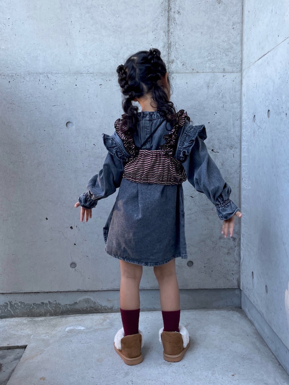 ブラウン系のショルダーバッグ、レッド系のキャミソール、ブラウン系のブーツを着用したキッズの秋コーディネートの3枚目の写真