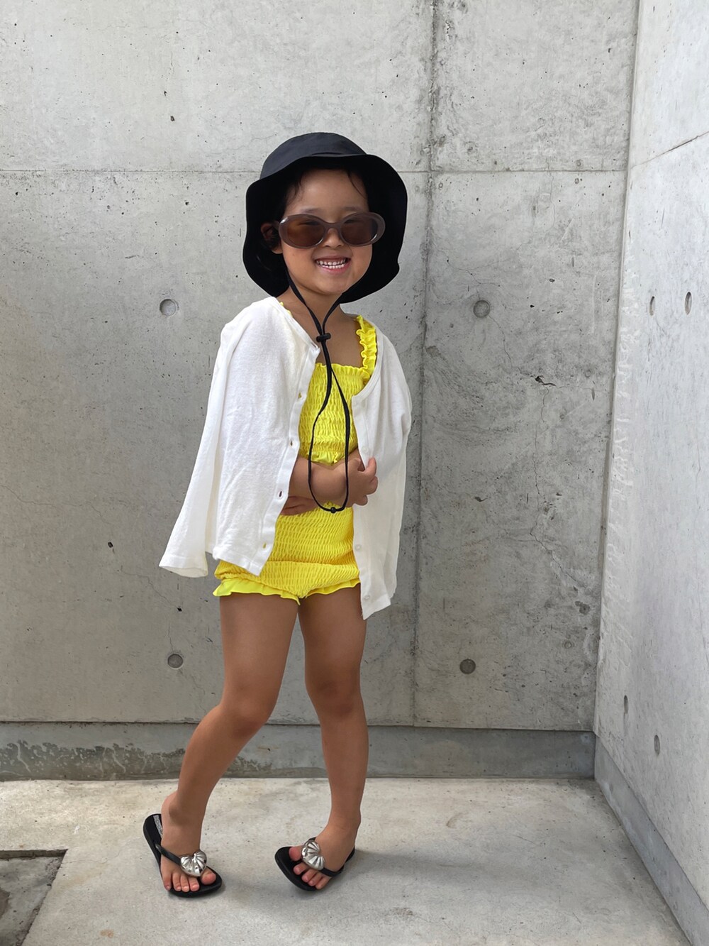 ブラック系のサンダル、イエロー系の水着、ブラック系のハットを着用したキッズの夏コーディネートの5枚目の写真