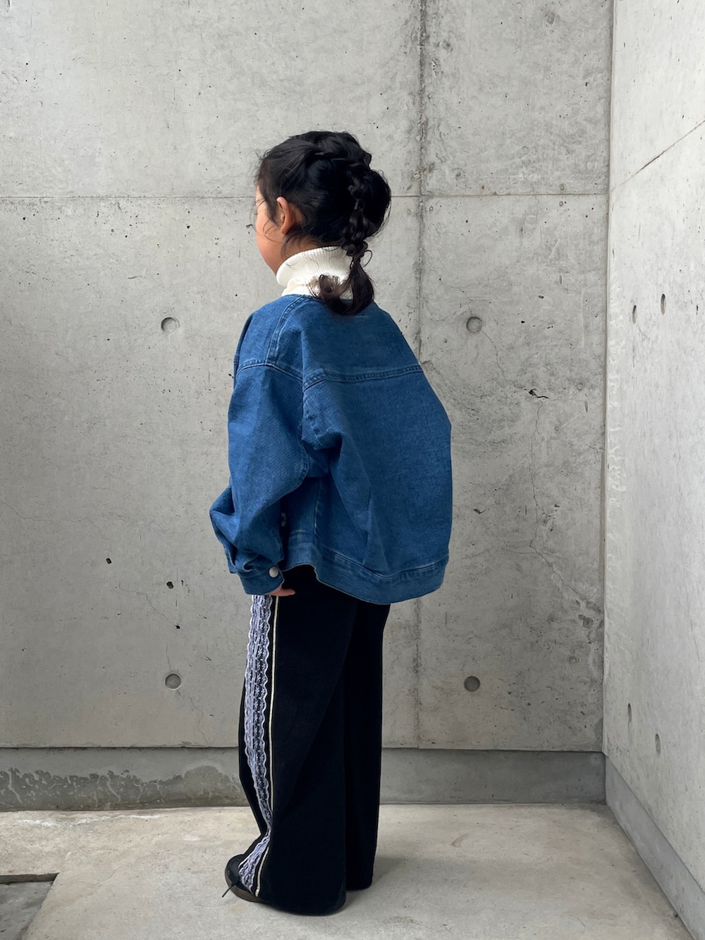 ブラック系のパンツ、ブルー系のデニムジャケット、ホワイト系のニット/セーターを着用したキッズの春コーディネートの5枚目の写真