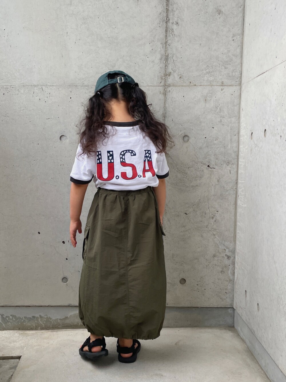 ホワイト系のTシャツ/カットソー、グリーン系のスカート、ブラック系のサンダルを着用したキッズの夏コーディネートの2枚目の写真