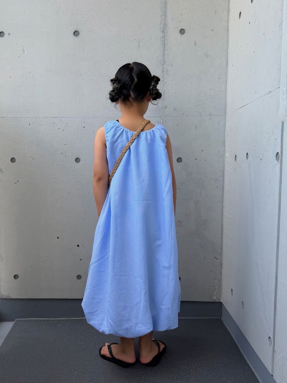 ブルー系のワンピース、ベージュ系のショルダーバッグ、ブラック系のサンダルを着用したキッズの夏コーディネートの4枚目の写真