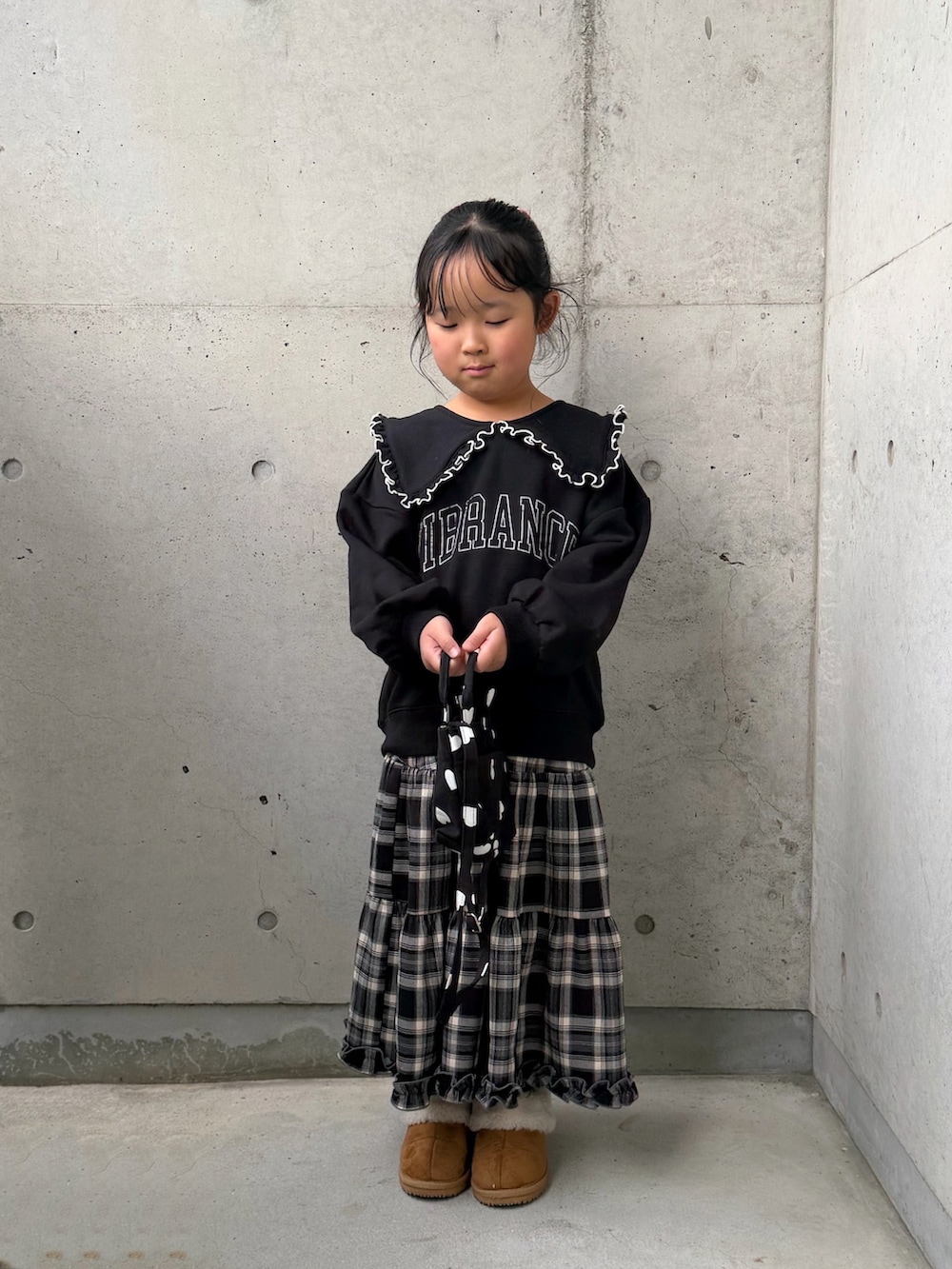 ブラック系のスウェット、ブラウン系のスカート、ブラック系のショルダーバッグを着用したキッズの秋コーディネートの5枚目の写真