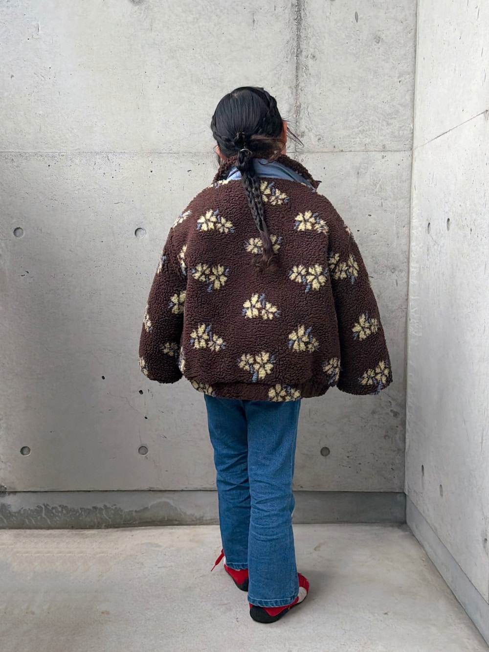 レッド系のニット/セーター、レッド系のスニーカー、ブルー系のデニムジャケットを着用したキッズの冬コーディネートの3枚目の写真