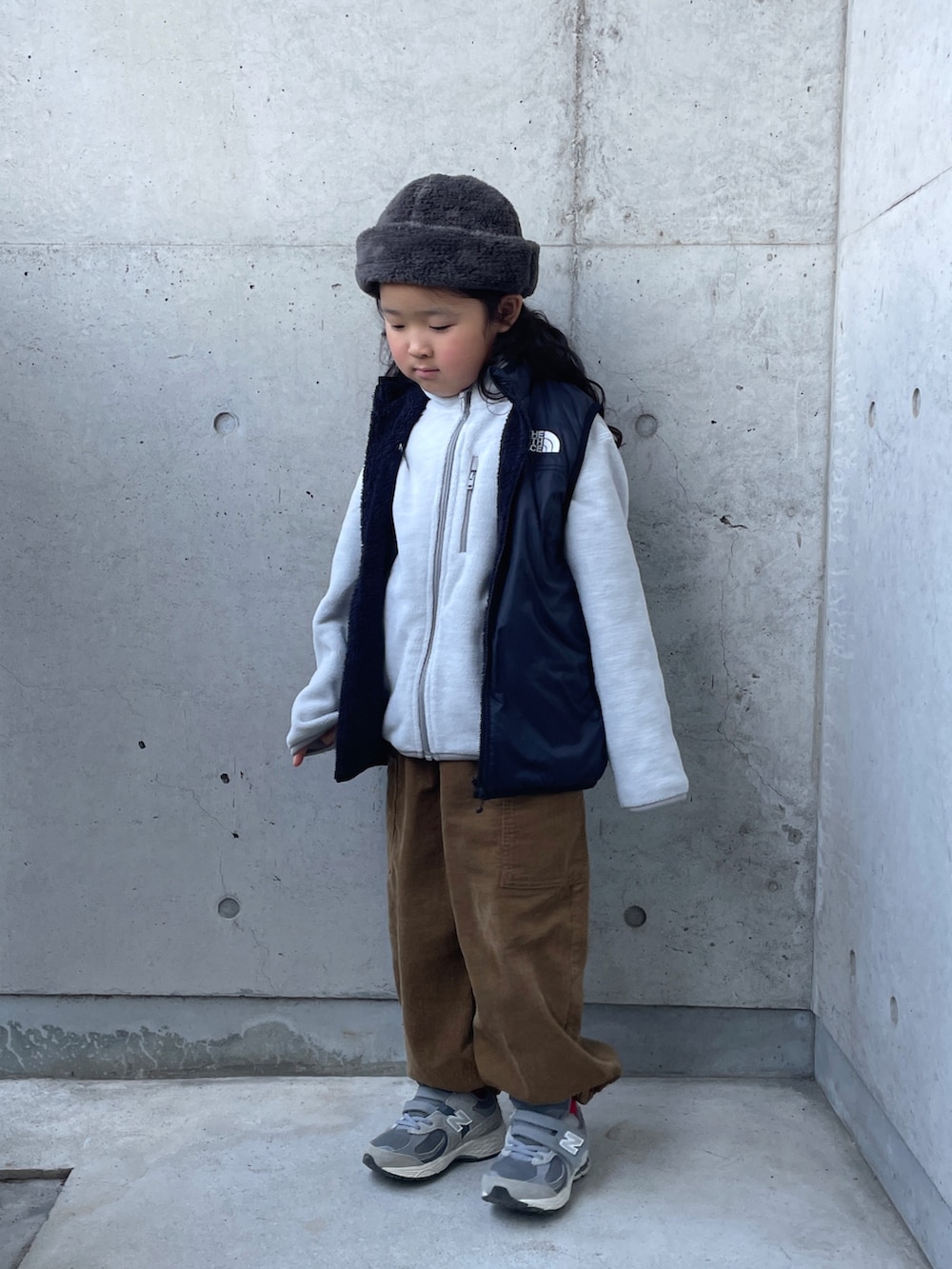 グレー系のトップス、ブラック系のベスト、イエロー系のその他パンツを着用したキッズの冬コーディネートの4枚目の写真