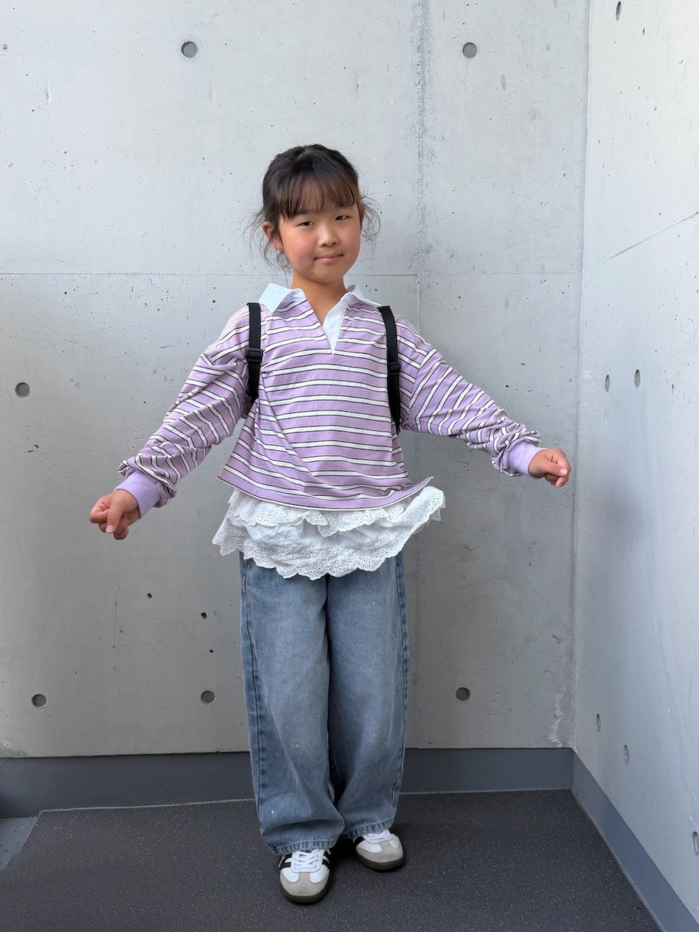 ブルー系のデニムパンツ、ブラック系のバックパック/リュック、パープル系のポロシャツを着用したキッズの秋コーディネートの4枚目の写真