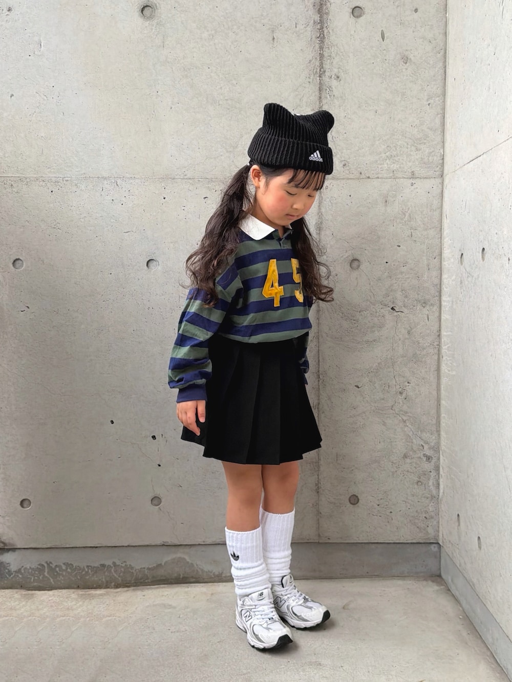 グリーン系のポロシャツ、ホワイト系のスニーカー、ブラック系のパンツを着用したキッズの冬コーディネートの4枚目の写真