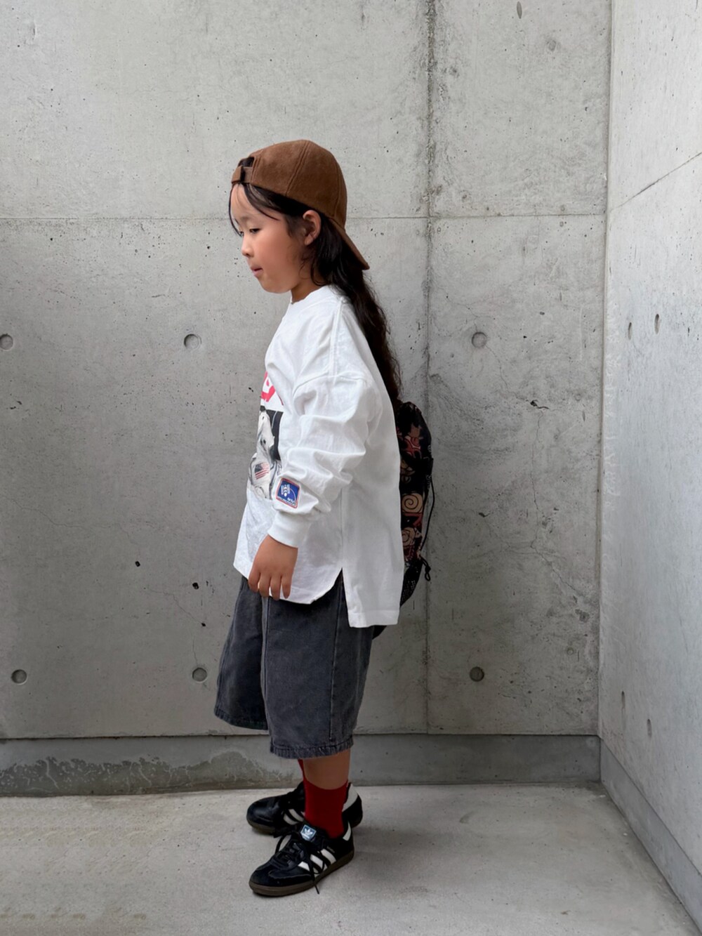 ブラック系のスニーカー、ホワイト系のTシャツ/カットソー、ブラック系のデニムパンツを着用したキッズの秋コーディネートの4枚目の写真