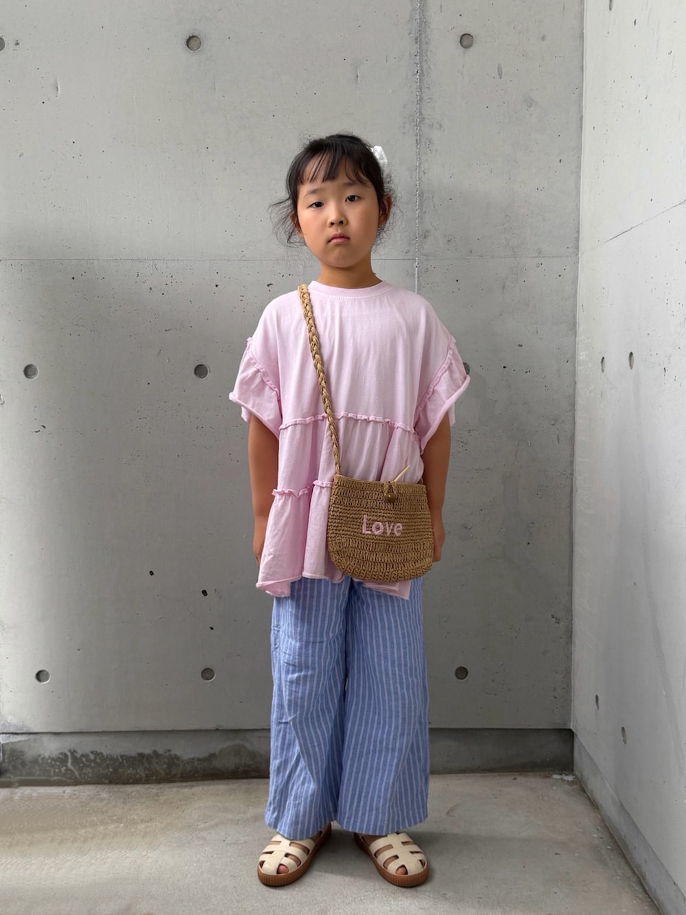 ピンク系のTシャツ/カットソー、ベージュ系のショルダーバッグ、ホワイト系のサンダルを着用したキッズの夏コーディネートの3枚目の写真