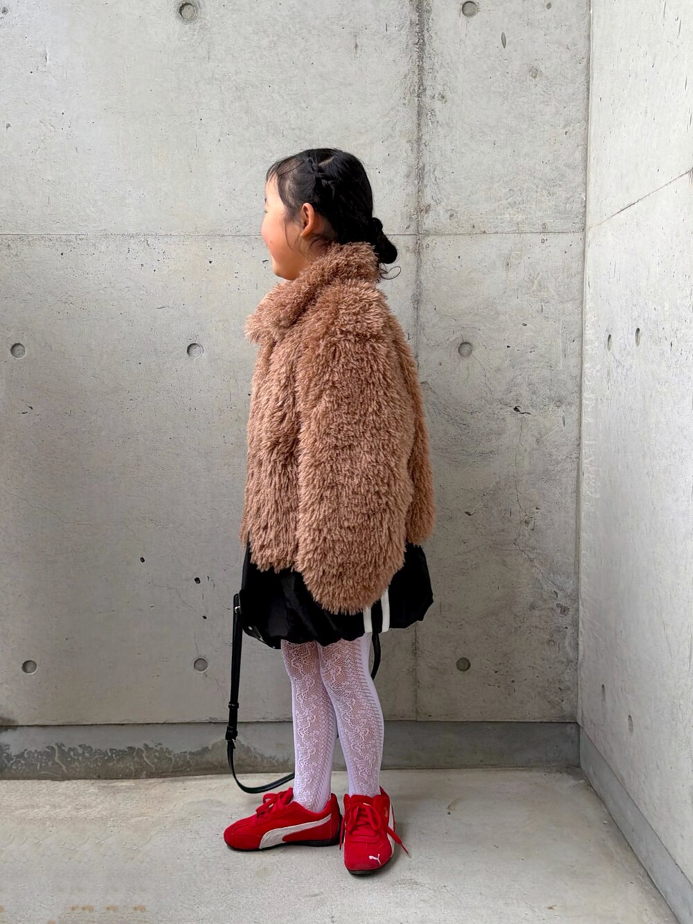 ブラウン系のブルゾン、ブラック系のスカート、ホワイト系のTシャツ/カットソーを着用したキッズの冬コーディネートの2枚目の写真