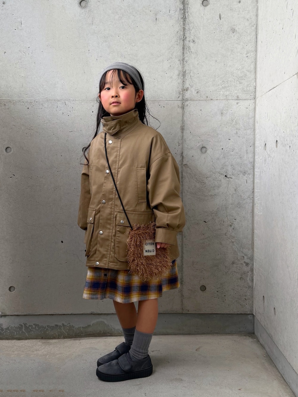 ベージュ系のミリタリージャケット、イエロー系のワンピース、グレー系のその他シューズを着用したキッズの冬コーディネートの5枚目の写真