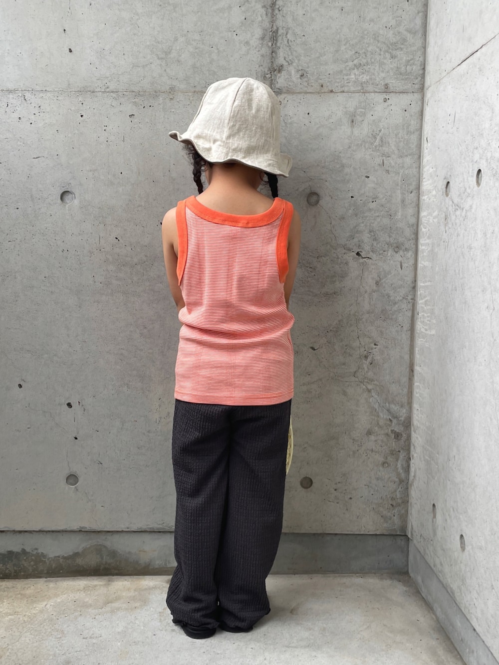 オレンジ系のタンクトップ、グレー系のその他パンツ、ホワイト系のバッグを着用したキッズの夏コーディネートの5枚目の写真
