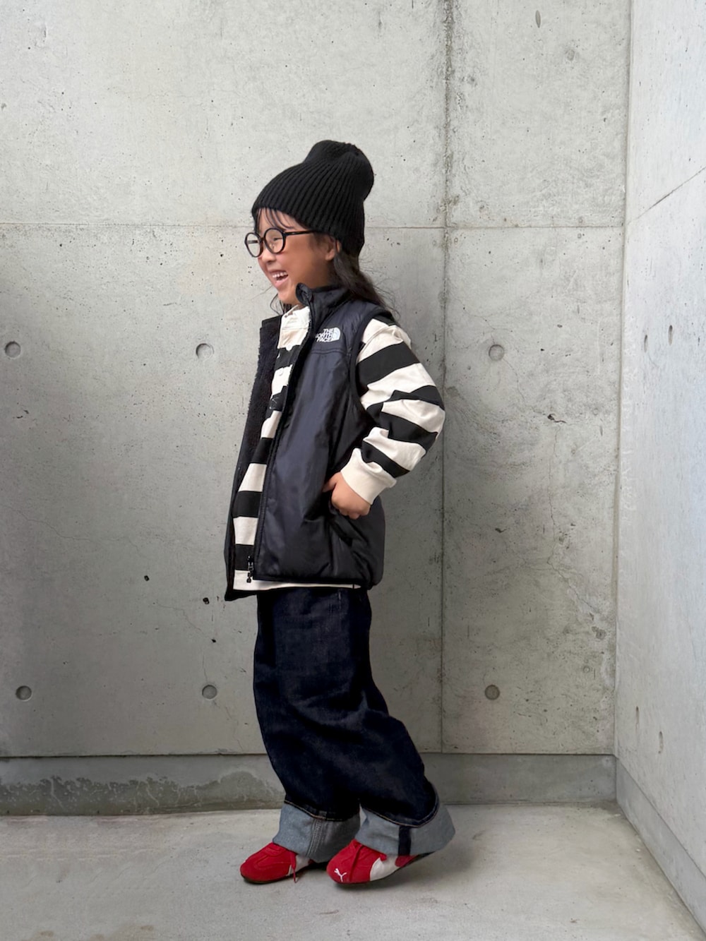 レッド系のスニーカー、ブラック系のベスト、ホワイト系のポロシャツを着用したキッズの秋コーディネートの4枚目の写真