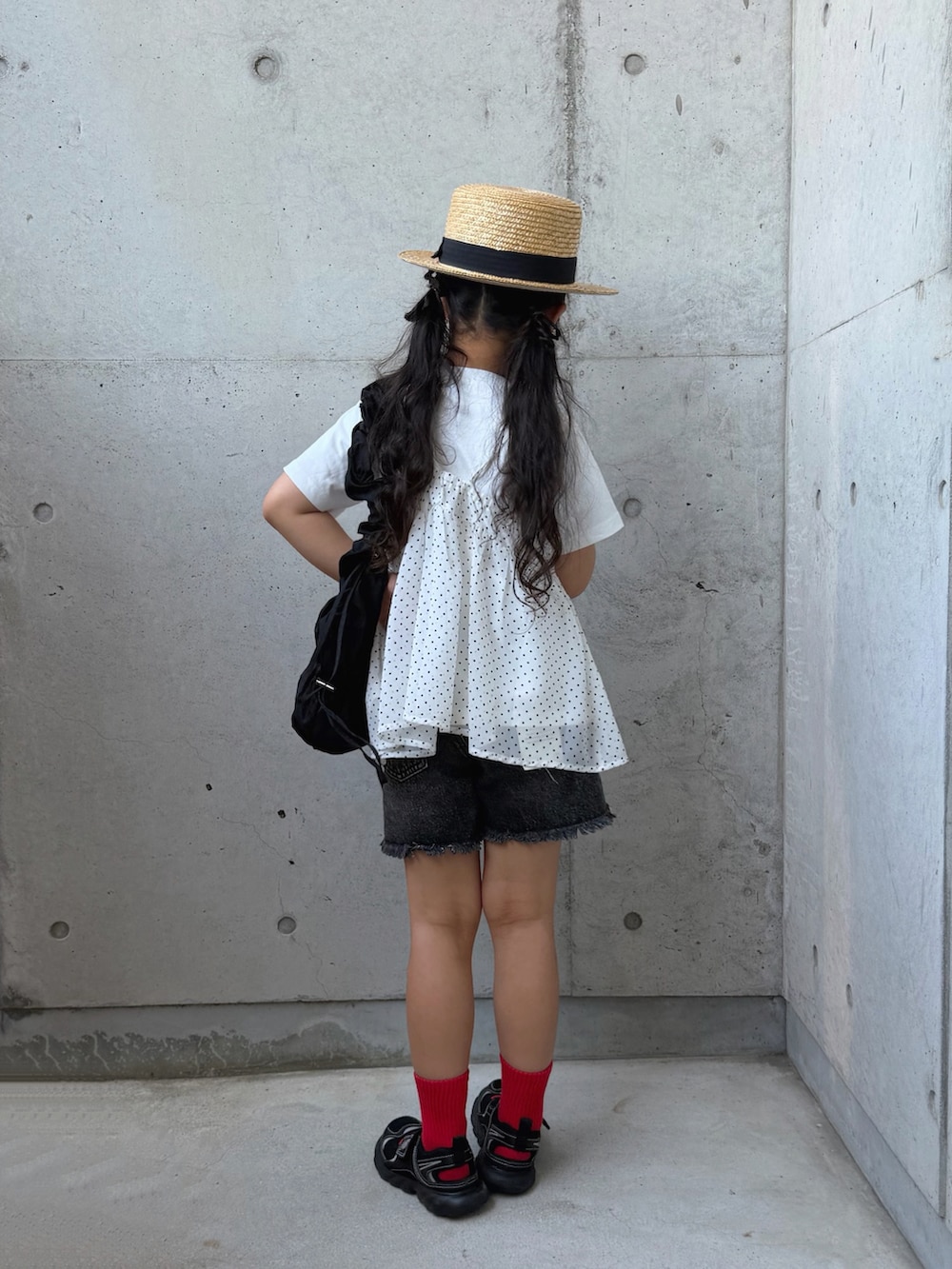 ブラック系のデニムパンツ、ホワイト系のTシャツ/カットソー、ブラック系のサンダルを着用したキッズの夏コーディネートの4枚目の写真