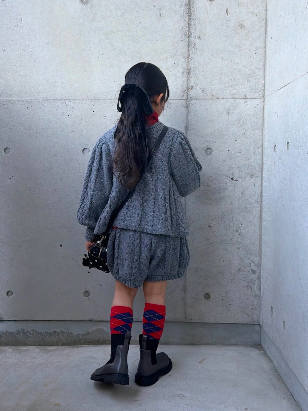 レッド系のニット/セーター、グレー系のニット/セーター、グレー系のその他パンツを着用したキッズの冬コーディネートの3枚目の写真