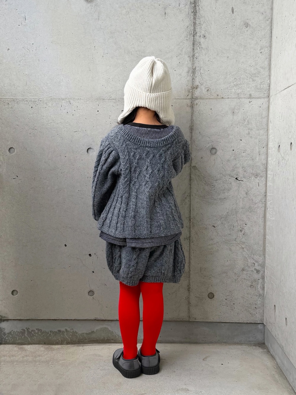 グレー系のニット/セーター、グレー系のその他パンツ、ブラック系のTシャツ/カットソーを着用したキッズの冬コーディネートの2枚目の写真