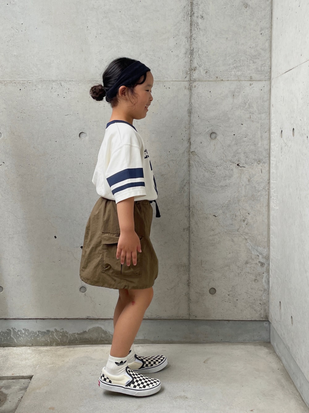 グリーン系のスカート、ブラック系のスリッポン、グリーン系のTシャツ/カットソーを着用したキッズの夏コーディネートの3枚目の写真