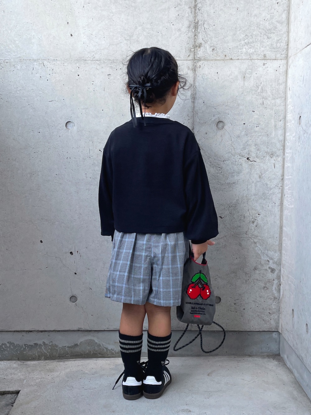 レッド系のパンツ、ブラック系のカーディガン/ボレロ、グレー系のショルダーバッグを着用したキッズの秋コーディネートの3枚目の写真