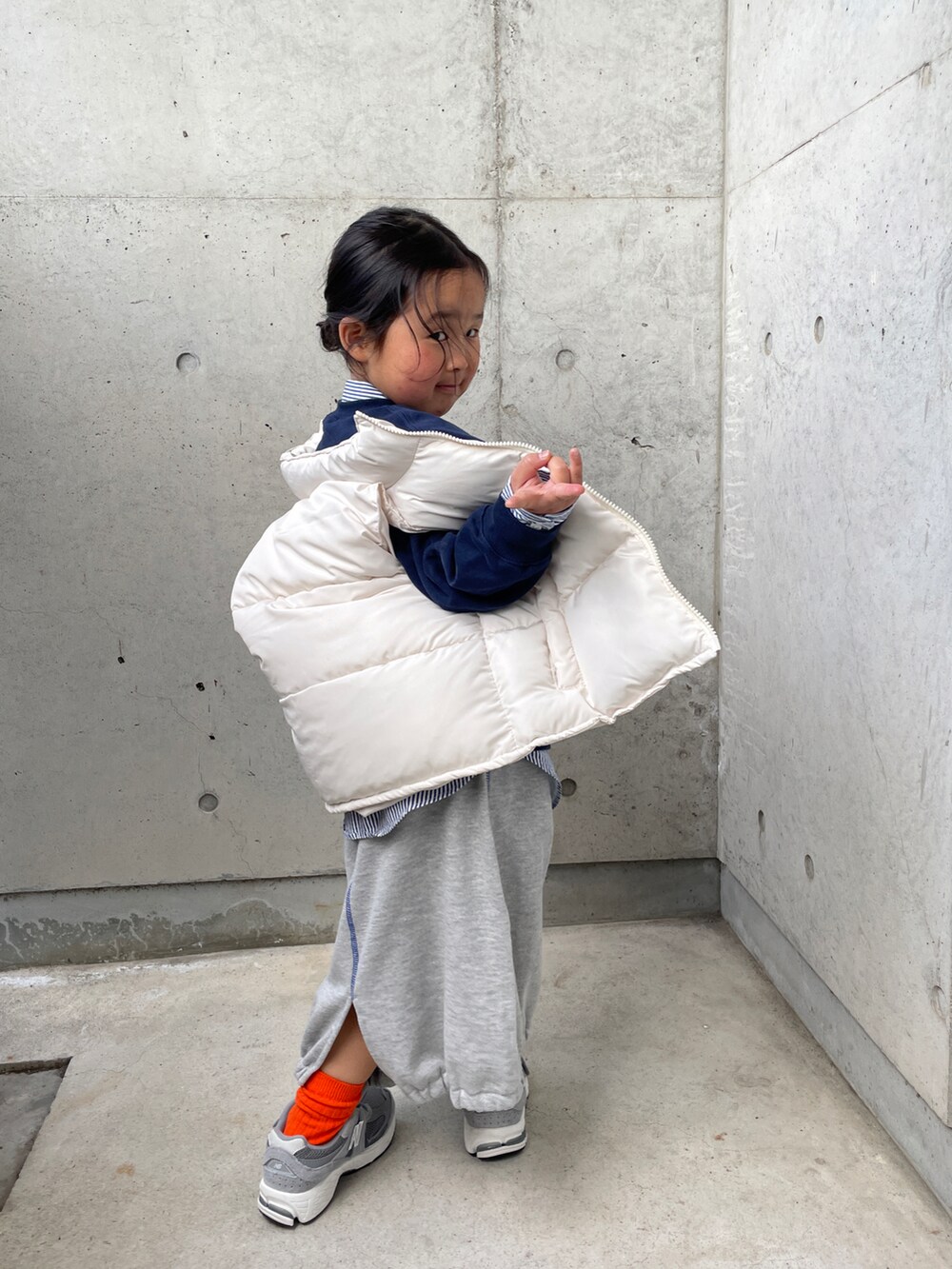 ホワイト系のダウンベスト、ブルー系のスウェット、グレー系のスカートを着用したキッズの春コーディネートの4枚目の写真