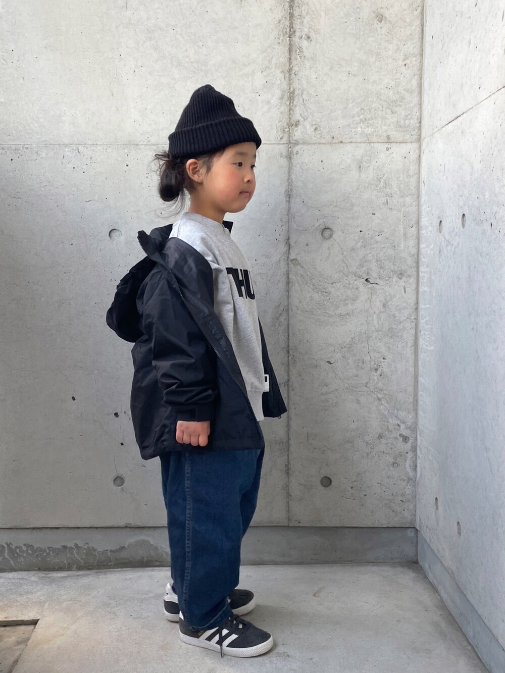 ブラック系のナイロンジャケット、グレー系のスウェット、ブルー系のデニムパンツを着用したキッズの冬コーディネートの2枚目の写真