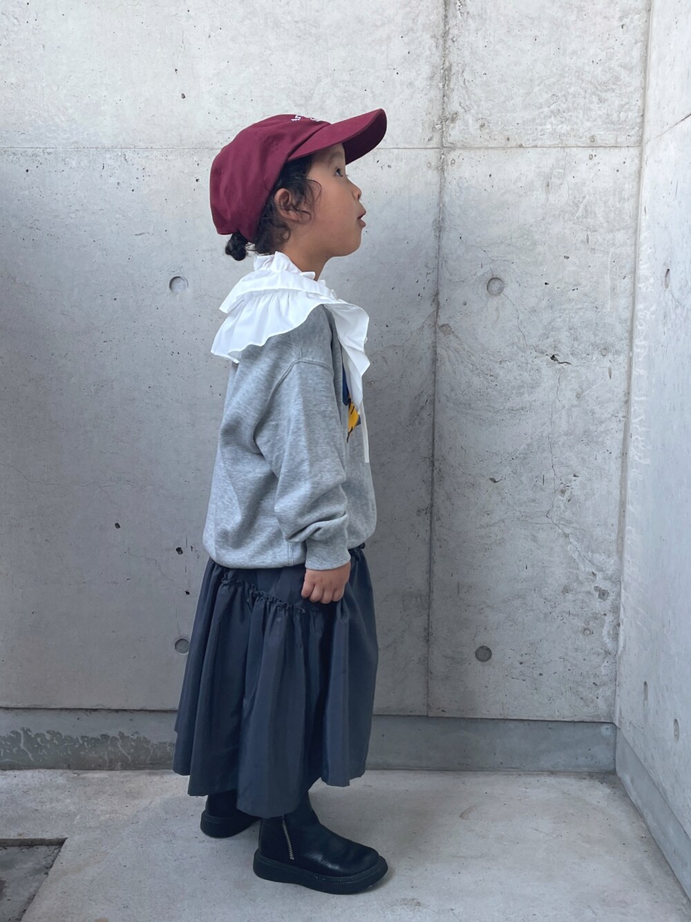 グレー系のワンピース、ブラック系のブーツ、グレー系のトップスを着用したキッズの秋コーディネートの2枚目の写真