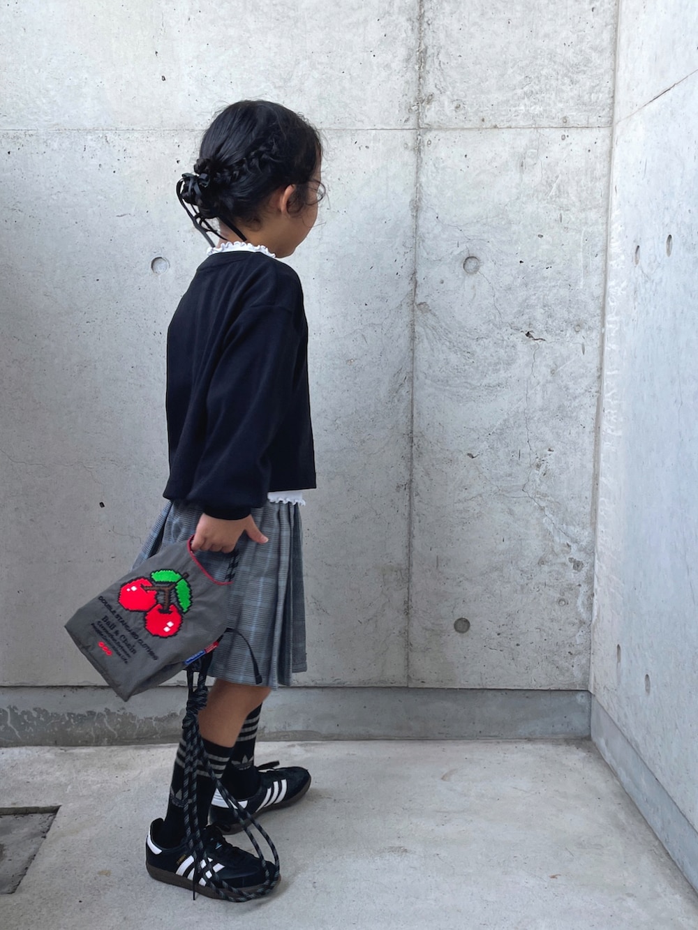 レッド系のパンツ、ブラック系のカーディガン/ボレロ、グレー系のショルダーバッグを着用したキッズの秋コーディネートの4枚目の写真