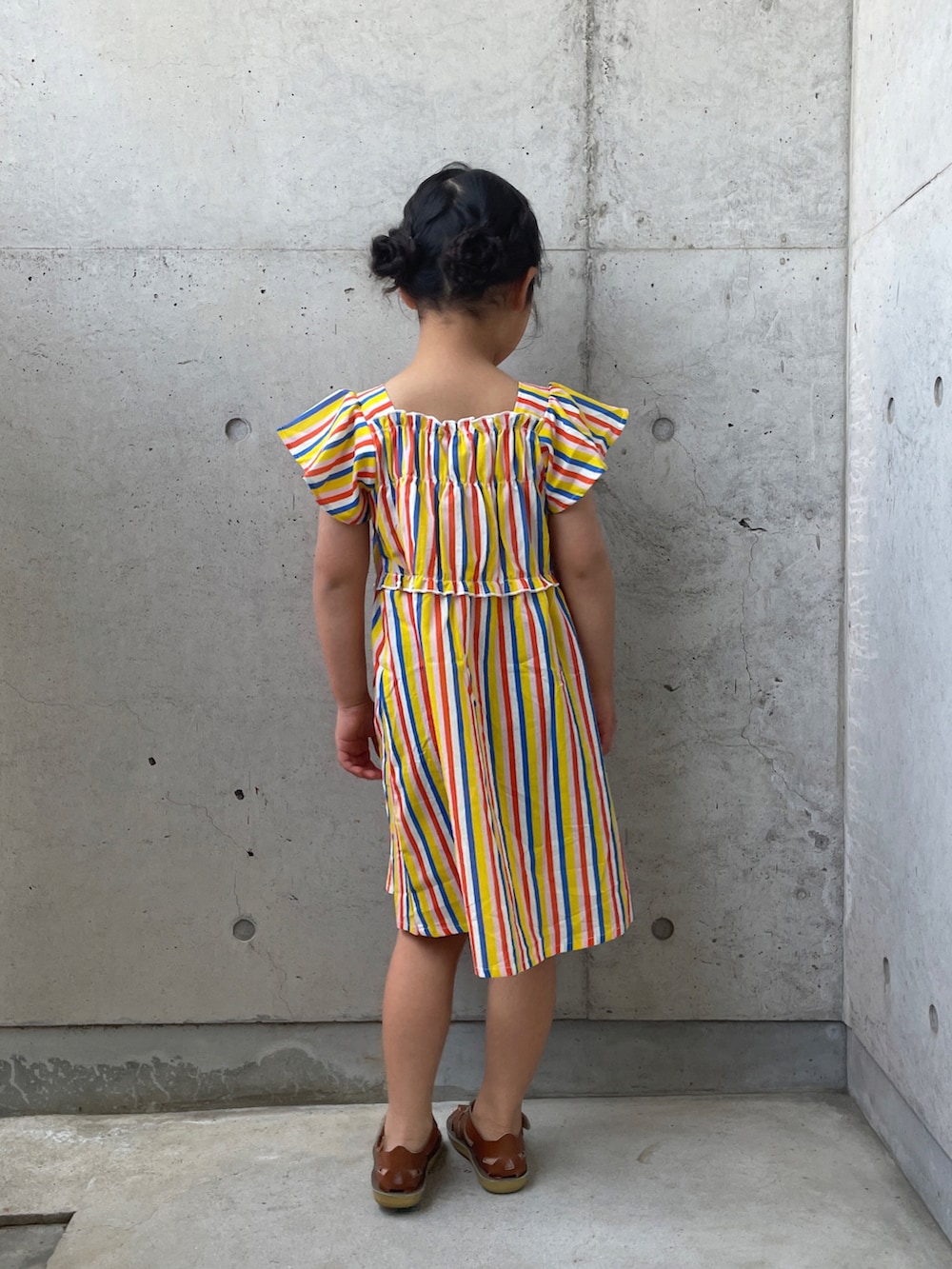 ベージュ系のサンダル、イエロー系のワンピースを着用したキッズの春コーディネートの3枚目の写真