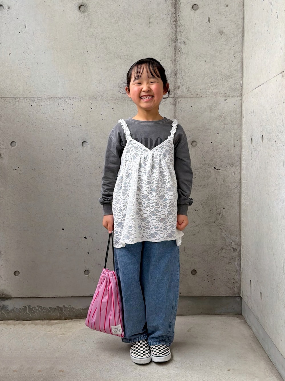 ピンク系のトートバッグ、ブラック系のスリッポン、ホワイト系のトップスを着用したキッズの春コーディネートの4枚目の写真