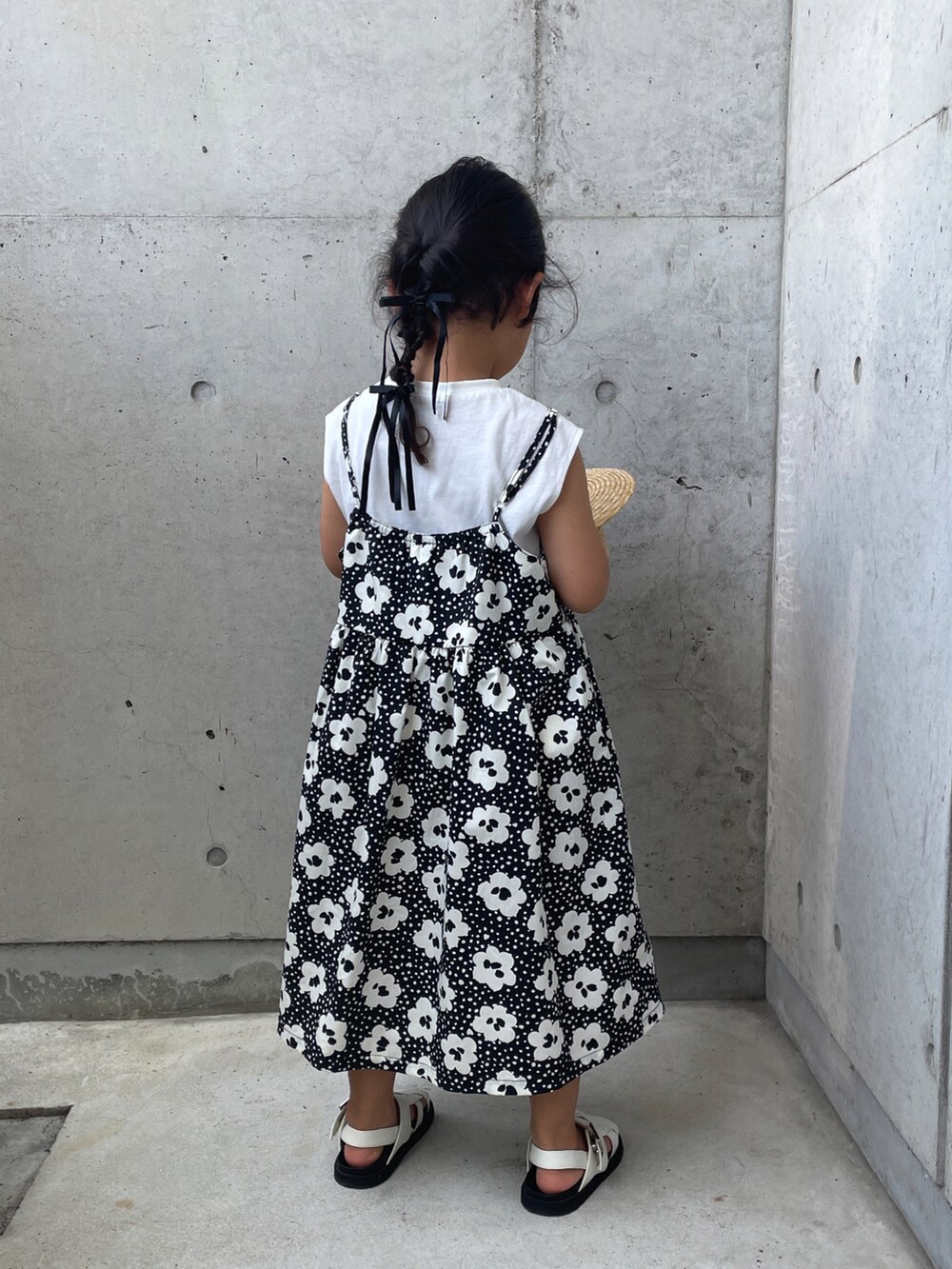ブラック系のワンピース、ホワイト系のサンダル、ベージュ系のハットを着用したキッズの夏コーディネートの4枚目の写真