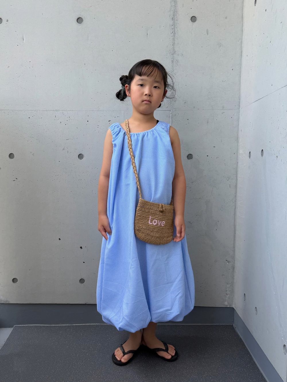 ブルー系のワンピース、ベージュ系のショルダーバッグ、ブラック系のサンダルを着用したキッズの夏コーディネートの3枚目の写真