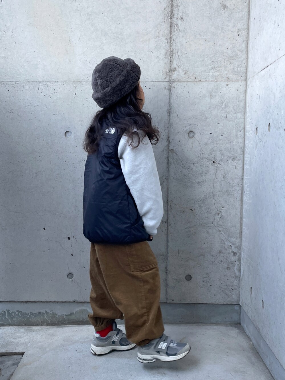 グレー系のトップス、ブラック系のベスト、イエロー系のその他パンツを着用したキッズの冬コーディネートの5枚目の写真