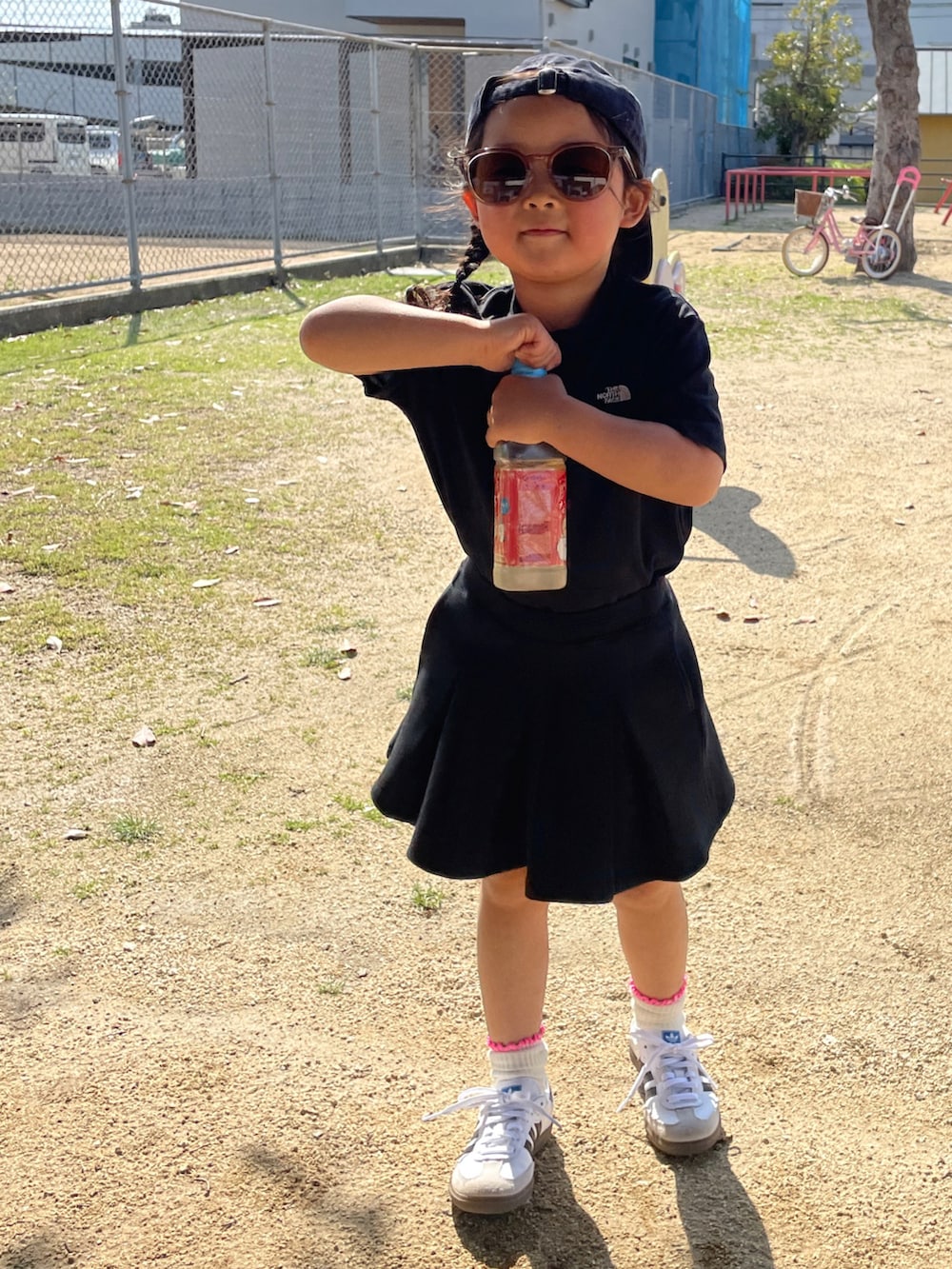 ブラック系のワンピース、ブラック系のスカート、ホワイト系のスニーカーを着用したキッズの春コーディネートの2枚目の写真