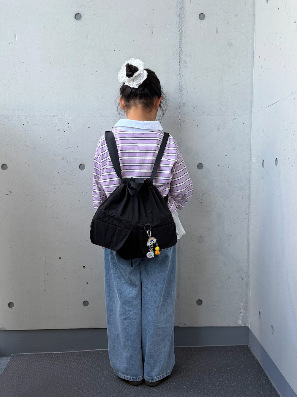 ブルー系のデニムパンツ、ブラック系のバックパック/リュック、パープル系のポロシャツを着用したキッズの秋コーディネートの3枚目の写真