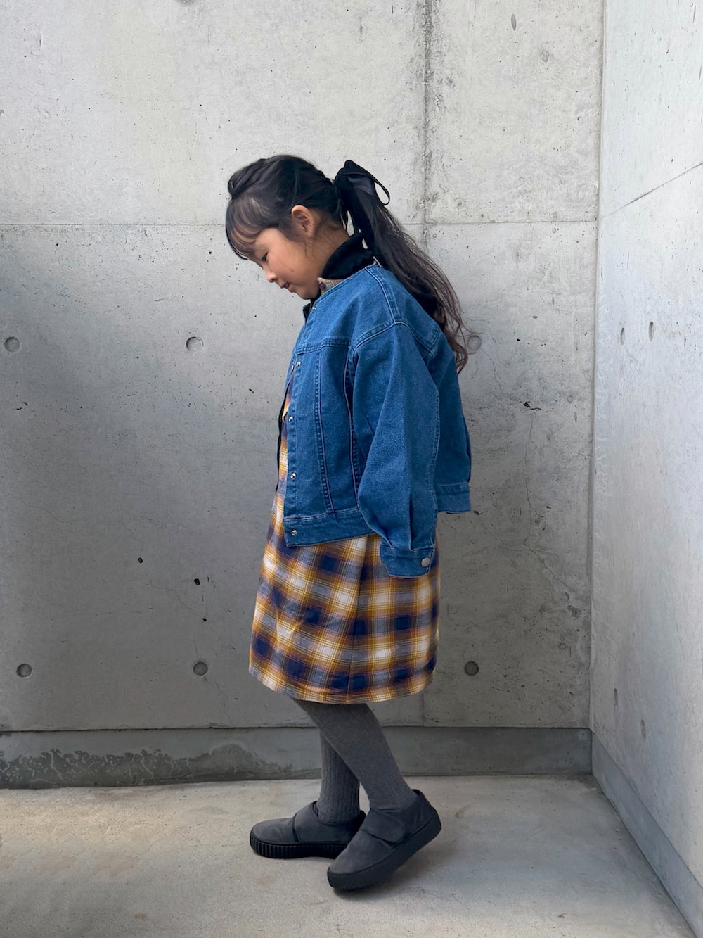 イエロー系のワンピース、グレー系のその他シューズ、ブラック系のニット/セーターを着用したキッズの冬コーディネートの2枚目の写真