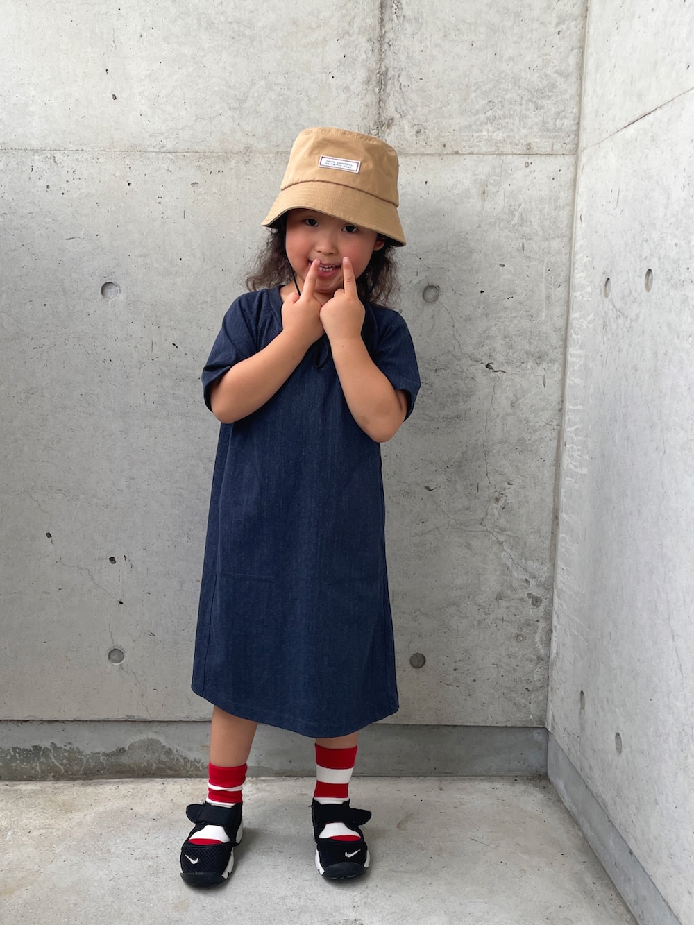 ブラック系のサンダル、ブルー系のワンピース、ベージュ系のハットを着用したキッズの夏コーディネートの4枚目の写真