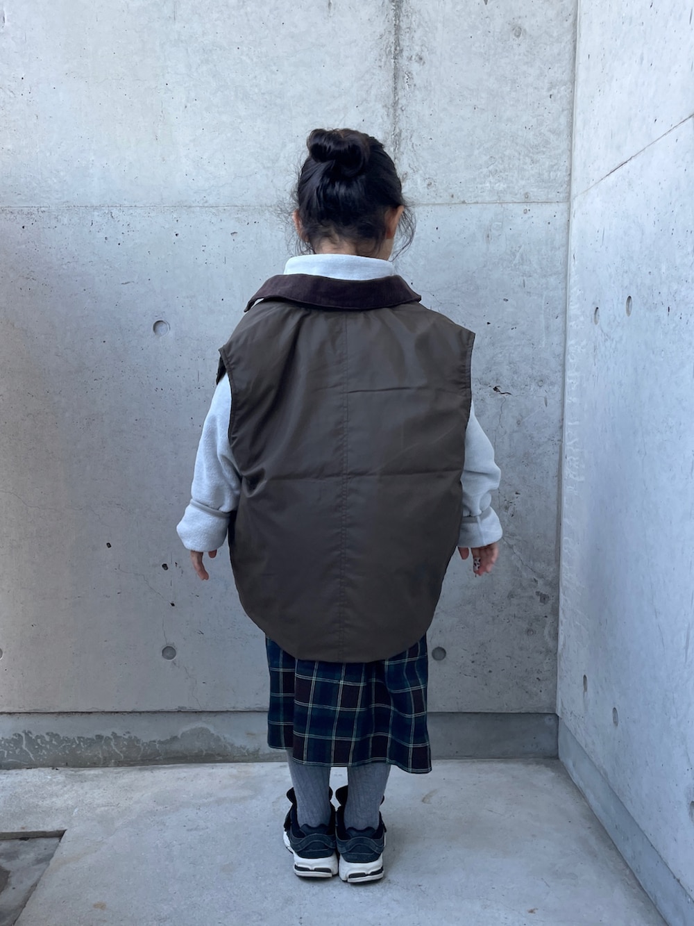 グレー系のトップス、グレー系のTシャツ/カットソー、ブラウン系のスカートを着用したキッズの冬コーディネートの2枚目の写真