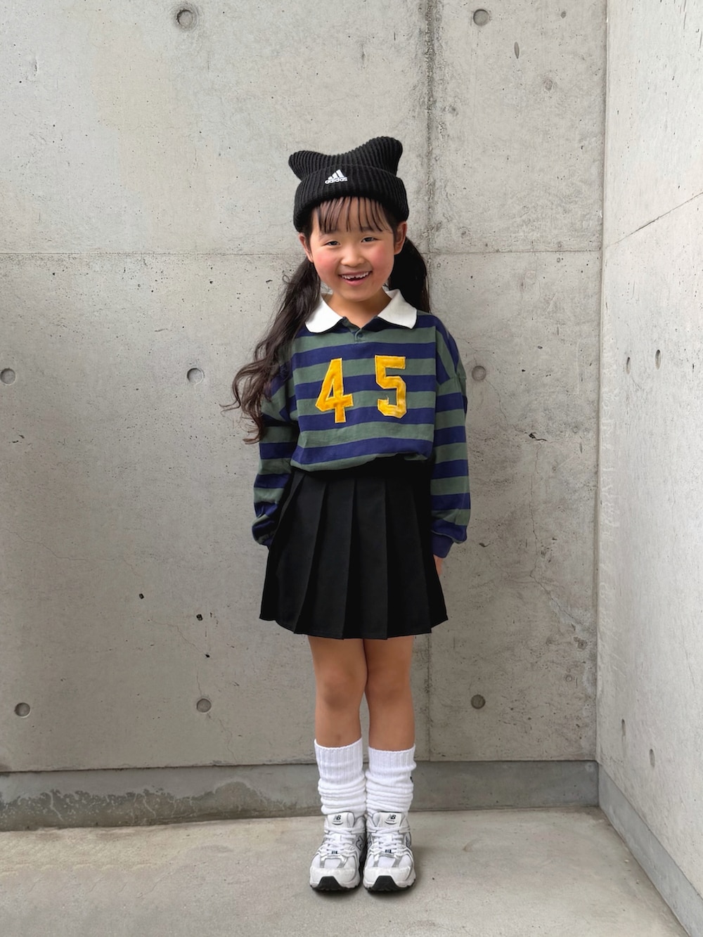 グリーン系のポロシャツ、ホワイト系のスニーカー、ブラック系のパンツを着用したキッズの冬コーディネートの5枚目の写真